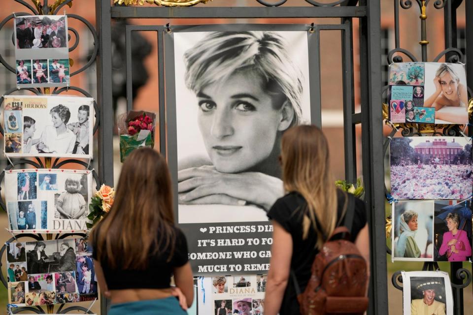 Two women look at portraits of Princess Diana and other remembrances displayed on the gates of Kensington Palace (AP)