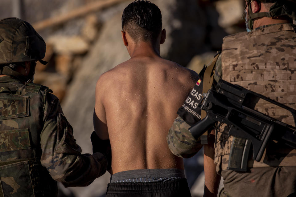 A migrant is escorted by Spanish army soldiers after arriving at the Spanish enclave of Ceuta, near the border of Morocco and Spain, Wednesday, May 19, 2021. Spanish officials are acknowledging for the first time that the unprecedented migrant crisis has been triggered by an angry Rabat at Madrid's decision to provide medical treatment to the militant boss of the Polisario Front. (AP Photo/Bernat Armangue)