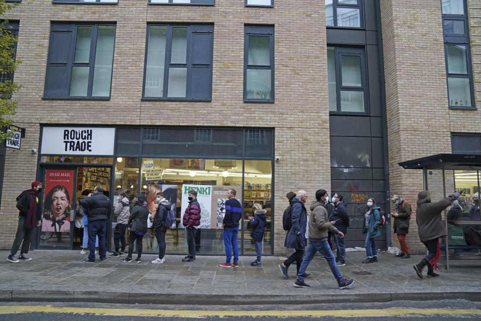 People queue outside Rough Trade in Bristol, England, Saturday Dec. 11, 2021, where a T-shirt designed by street artist Banksy is being sold to support four people facing trial accused of criminal damage in relation to the toppling of a statue of slave trader Edward Colston. The anonymous artist posted on Instagram pictures of limited edition grey souvenir T-shirts which will go on sale on Saturday in Bristol. The shirts have a picture of Colston's empty plinth with a rope hanging off, with debris and a discarded sign nearby. (Jacob King/PA via AP)