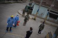 Escorted by soldiers, Doctor Jose Pimentel, left, and laboratory worker Adriana Morales, talk to a neighbor during a house-to-house coronavirus testing drive in Villa el Salvador on the outskirts of Lima, Peru, Tuesday, June 30, 2020. (AP Photo/Rodrigo Abd)