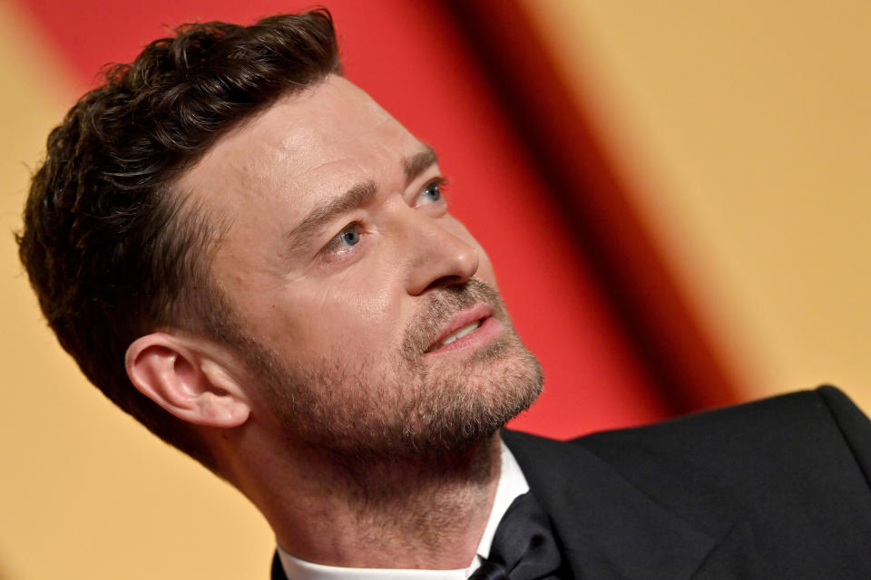 Justin Timberlake in a formal suit looking up, with a blurred background