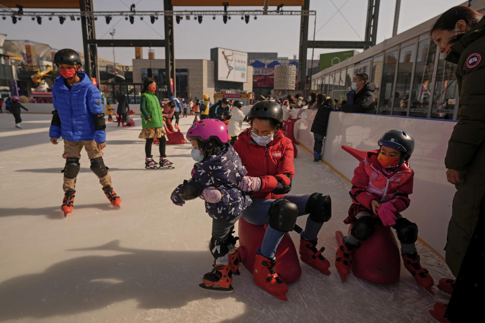 Residents bring their children play ice skating at a mall next to a venue which host the men's and women's ice hockey games at the 2022 Winter Olympics in Beijing, Thursday, Feb. 10, 2022. The possibility of a large outbreak in the Olympic bubble, potentially sidelining athletes from competitions, has been a greater fear than any leakage into the rest of China. (AP Photo/Andy Wong)