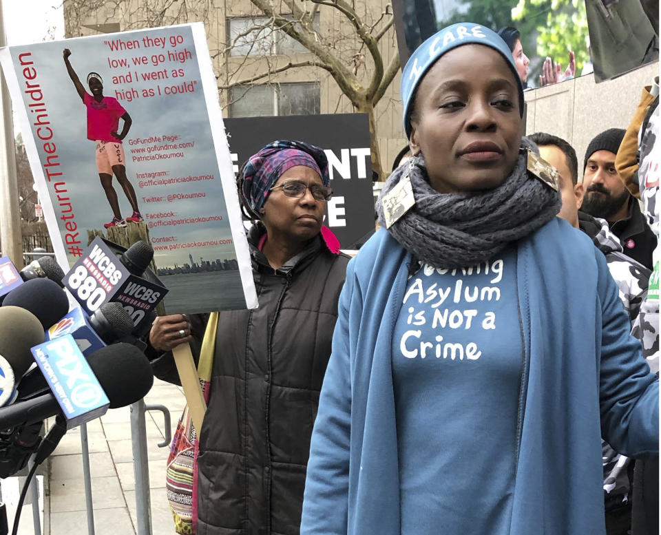 Therese Okoumou, right, who climbed the base of the Statue of Liberty on July 4 to protest the separation of families at the Mexican border, stands next to a poster of herself outside a courthouse in lower Manhattan after she was convicted of misdemeanor charges Monday, Dec. 17, 2018, in New York. The charges include trespassing and carry a potential penalty of up to 18 months in prison. (AP Photo/Lawrence Neumeister)