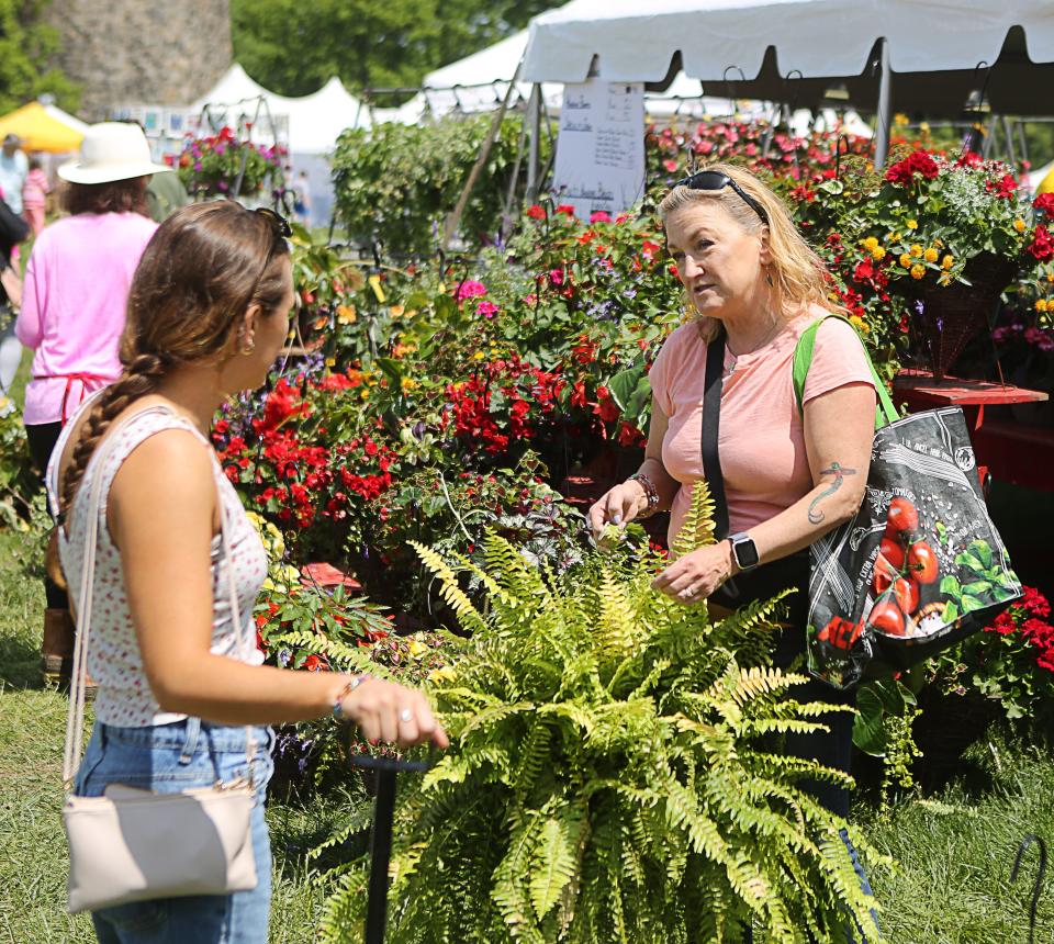 Molly Hernandez, of Garnet Valley, shows her daughter Jamie a tiger fern available for sale at the Wilmington Flower Market on Thursday May 11, 2023.