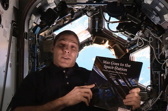 NASA astronaut Michael Hopkins holds a copy of "Max Goes to the Space Station," the first children's book to be read onboard the International Space Station as part of "Story Time From Space," an educational outreach project.