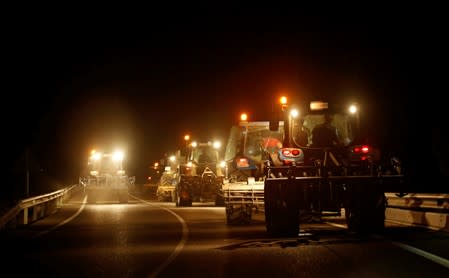 Farmers with their tractors travel down a road to set up firewalls and remove dry plants during a forest fire near Maials, west of Tarragona