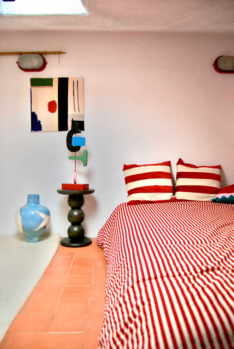 Bed with red and white striped bedding in light bedroom.