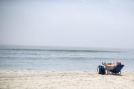 A man sunbathes on the beach maintaining proper social distancing, Wednesday, May 27, 2020, in Long Beach, N.Y. The Long Beach beach is open only to the city's residents. Long Island has become the latest region of New York to begin easing restrictions put in place to curb the spread of the coronavirus as it enters the first phase of the state's four-step reopening process. (AP Photo/Mary Altaffer)