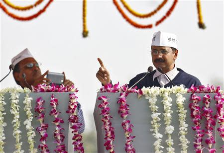 A supporter of Arvind Kejriwal (R), leader of Aam Aadmi (Common Man) Party (AAP), uses his mobile phone to take photo of Kejriwal addressing his supporters after taking oath as the new chief minister of Delhi during a swearing-in ceremony at Ramlila grounds in New Delhi December 28, 2013. REUTERS/Anindito Mukherjee