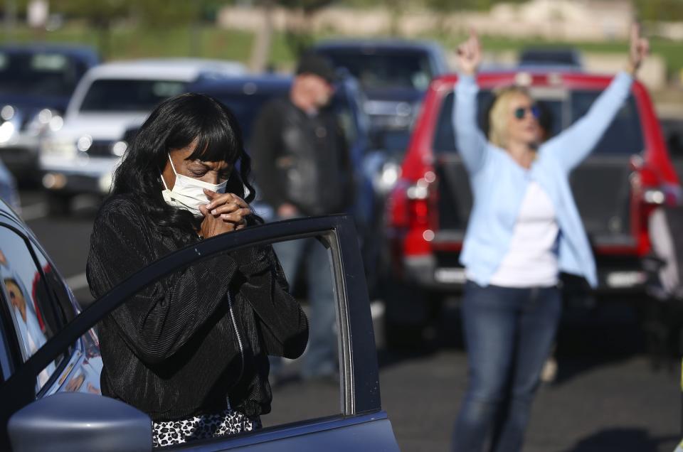Keeping to safe social distance guidelines, worshipers pray at their own vehicles as they attend an outside drive-in Easter service at the Living Word church due to the coronavirus Sunday, April 12, 2020, in Mesa, Ariz. (AP Photo/Ross D. Franklin)