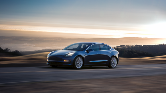 A blue Model 3 driving on an open road