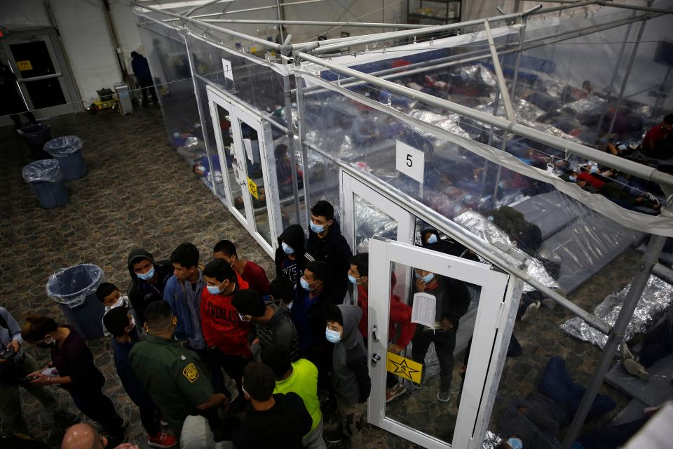 Minors talk to an agent outside a pod at the Department of Homeland Security holding facility run by the Customs and Border Patrol (CBP) on March 30, 2021 in Donna, Texas. The Donna location is the main detention center for unaccompanied children coming across the U.S. border in the Rio Grande Valley. The children are housed by the hundreds in eight pods that are about 3,200 square feet in size. Many of the pods had more than 500 children in them. The youngest of the unaccompanied minors are kept separate from the rest of the detainees. The Biden administration has just allowed journalists inside its main detention facility at the border for migrant children. It is an overcrowded tent structure where more than 4,000 kids and families are kept in pods, with the youngest kept in a large play pen with mats on the floor for sleeping. (Photo by Dario Lopez-Mills - Pool/Getty Images)