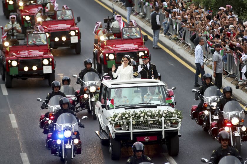 Jordan's Crown Prince Hussein and Saudi Rajqa Alseif wave to well-wishers during their wedding ceremonies in Amman, Jordan, Thursday, June 1, 2023. (AP Photo/Raad Adayleh)