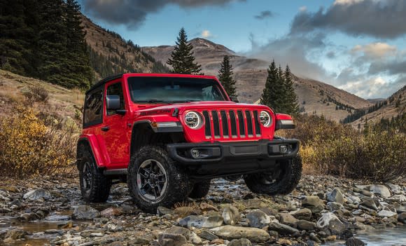 A red Jeep Wrangler Rubicon on a gravel road in the mountains.