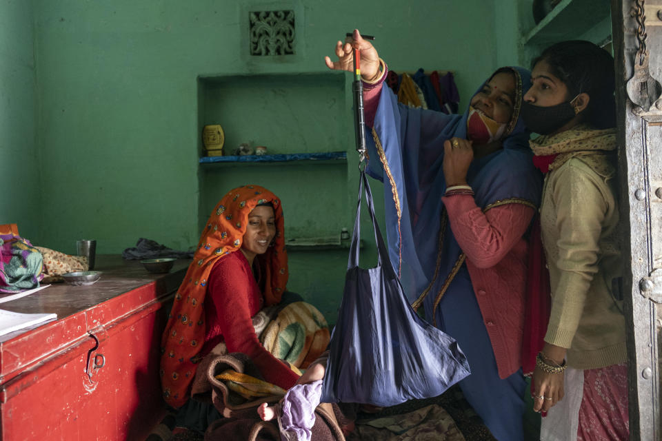 Bhanwar Bai Jadoun, en el centro, una activista social sanitaria acreditada, y Anita Chowdhary, a la derecha, una enfermera partera auxiliar, pesan a un recién nacido en Bagdoli, India, el 10 de febrero de 2022. (Saumya Khandelwal/The New York Times).