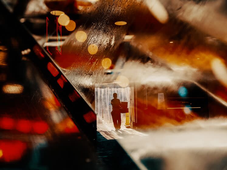 A double exposure of a man carrying boxes with the lights of Grand Central Market in downtown Los Angeles. / Bethany Mollenkof for the Los Angeles Times