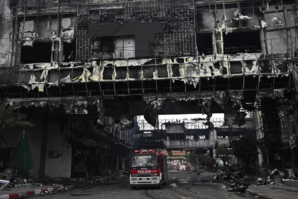 A police vehicle is pictured under a destroyed part of the Grand Diamond City hotel-casino following a major fire in Poipet on December 29, 2022. - About 10 people are dead and more than a dozen on life support after a fire at a Cambodian border casino, with photos from the scene showing people desperately huddled on ledges and perched on windowsills in a bid to escape the flames.