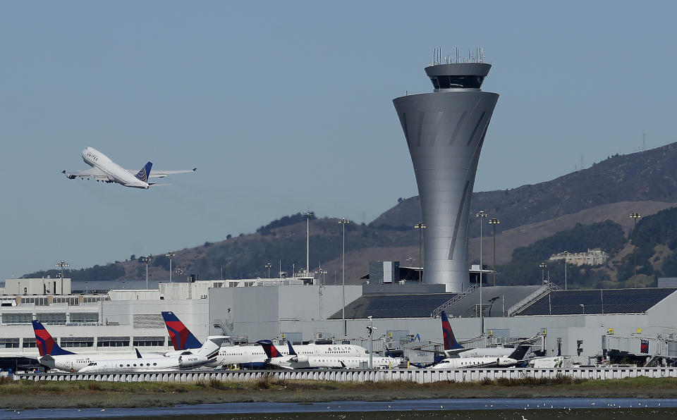 FILE - In this Oct. 24, 2107 file photo, the air traffic control tower is in sight as a plane takes off from San Francisco International Airport in San Francisco. San Francisco International Airport is banning the sale of single-use plastic water bottles. The change will take effect Aug. 20, 2019 and will apply to airport restaurants, cafes and vending machines. (AP Photo/Jeff Chiu, File)