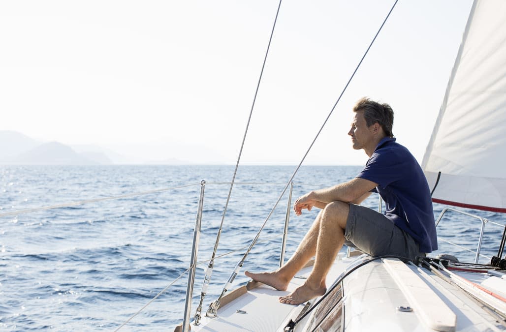 man sitting on bow of sailing yacht