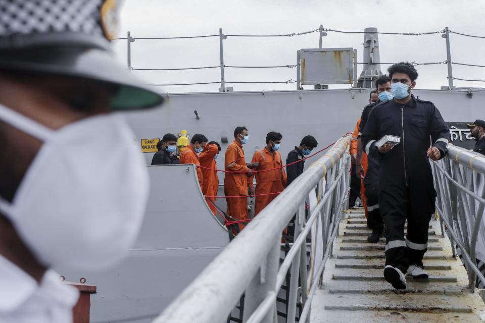 People rescued by the Indian navy from a barge that sank in the Arabian sea walk out from Indian naval ship INS Kochi in Mumbai, India, Wednesday, May 19, 2021. The barge carrying personnel deployed for offshore drilling sank off Mumbai as a deadly cyclone blew ashore this week. (AP Photo/Rajanish Kakade)