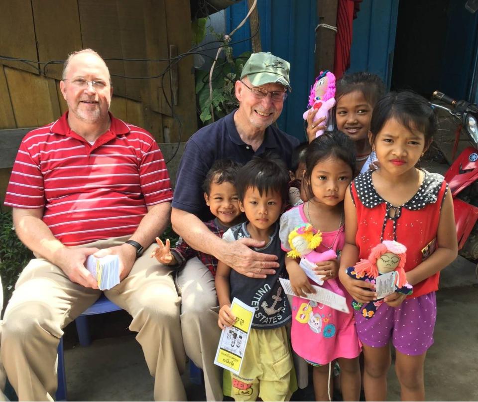 On a mission trip to Cambodia in 2017, Pastor Dr. Ray Haskett of Calvary Baptist Church and Dorsey Kimbrell present Dolls on a Mission dolls to children.
