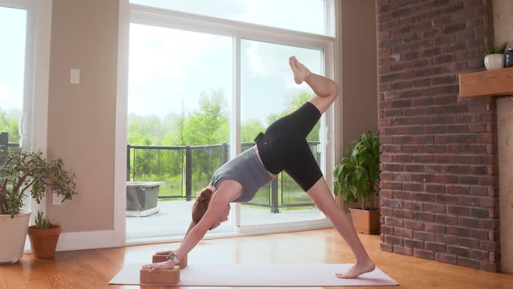 Yoga With Kassandra practicing Down Dog during a 20-minute power yoga flow with her top knee bent for greater hip stretch.