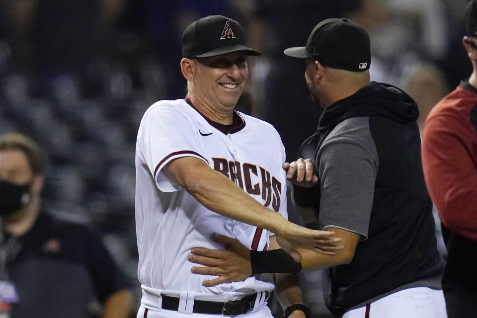 Arizona Diamondbacks manager Torey Lovullo, left, smiles as he celebrates a win against the Milwaukee Brewers with Diamondbacks' David Peralta, right, after the final out of the ninth inning of a baseball game Monday, June 21, 2021, in Phoenix. The Diamondbacks defeated the Brewers 5-1. (AP Photo/Ross D. Franklin)