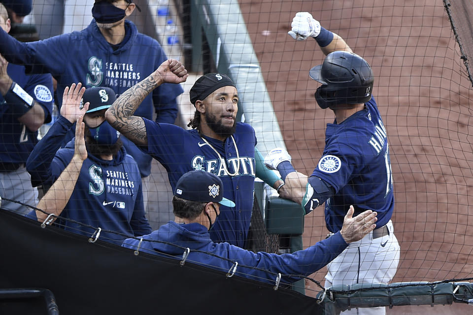 Mitch Haniger, de los Marineros de Seattle, llega a la cueva, donde es felicitado tras conectar un jonrón, en el segundo juego de una doble cartelera ante los Orioles de Baltimore, el jueves 15 de abril de 2021 (AP Foto/Gail Burton)