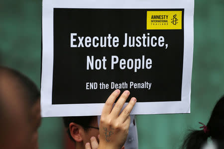 A demonstrator from Amnesty International holds a placard outside the Bang Kwang Central Prison to protest against the death penalty in Bangkok, Thailand, June 19, 2018. REUTERS/Athit Perawongmetha1