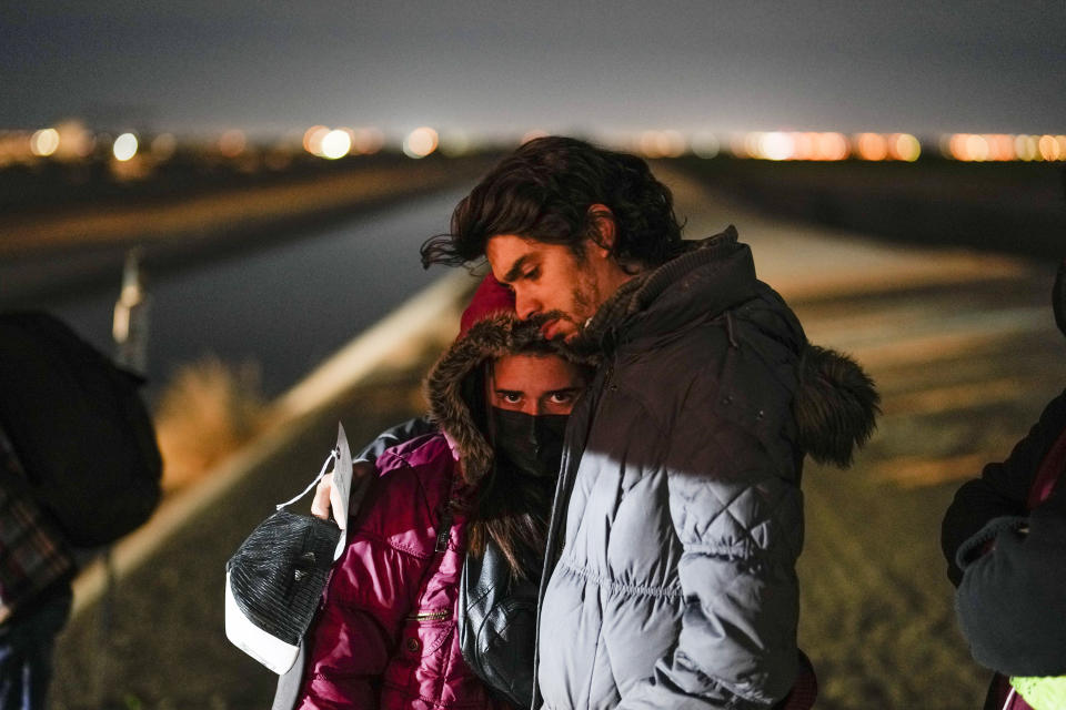 FILE - A couple from Cuba wait to be processed to seek asylum after crossing the border into the United States, Friday, Jan. 6, 2023, near Yuma, Ariz. An underground market has emerged for migrants seeking U.S. sponsors since the Biden administration announced last month that it would accept a limited number of people from Venezuela, Cuba, Nicaragua and Haiti. Applicants for the humanitarian parole program need someone in the U.S. to promise to provide financial support for at least two years. (AP Photo/Gregory Bull)