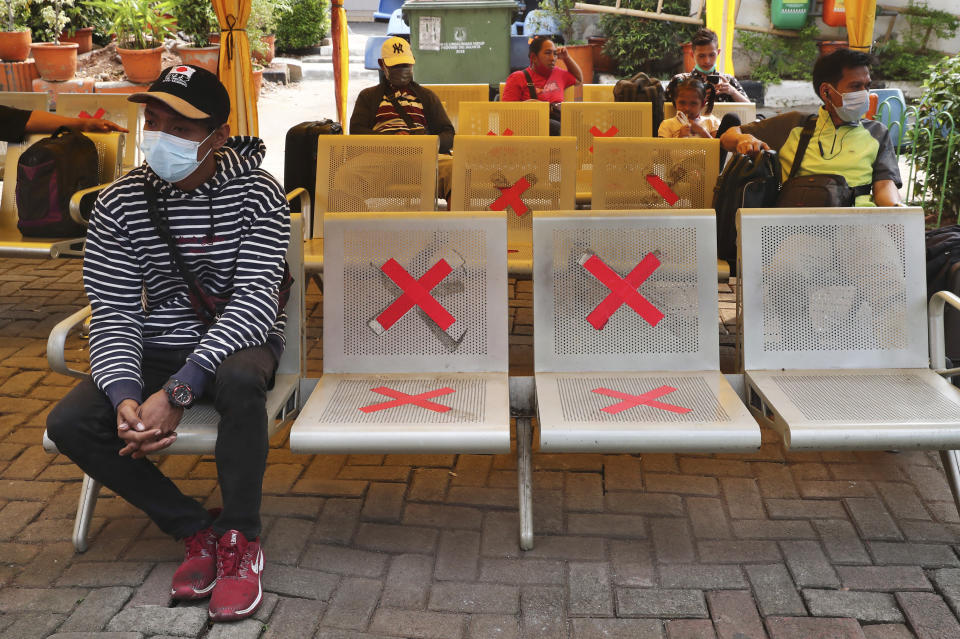 People sit among physical distancing markers as they wait for buses to go back to their home villages, at the Kalideres bus terminal in Jakarta, Indonesia, Wednesday, May 5, 2021. The mass exodus out of major cities in the world's most populous Muslim country is underway despite travel restrictions are imposed by the government to prevent the spread of the coronavirus outbreak, as people are heading home to their villages to celebrate Eid al-Fitr holiday that marks the end of the holy fasting month of Ramadan. (AP Photo/Tatan Syuflana)