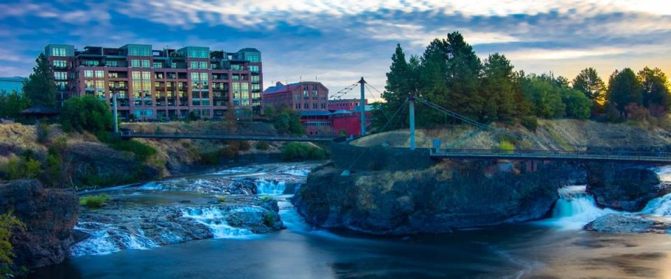 Sunrise over river and falls in downtown Spokane Washington with buildings in the background