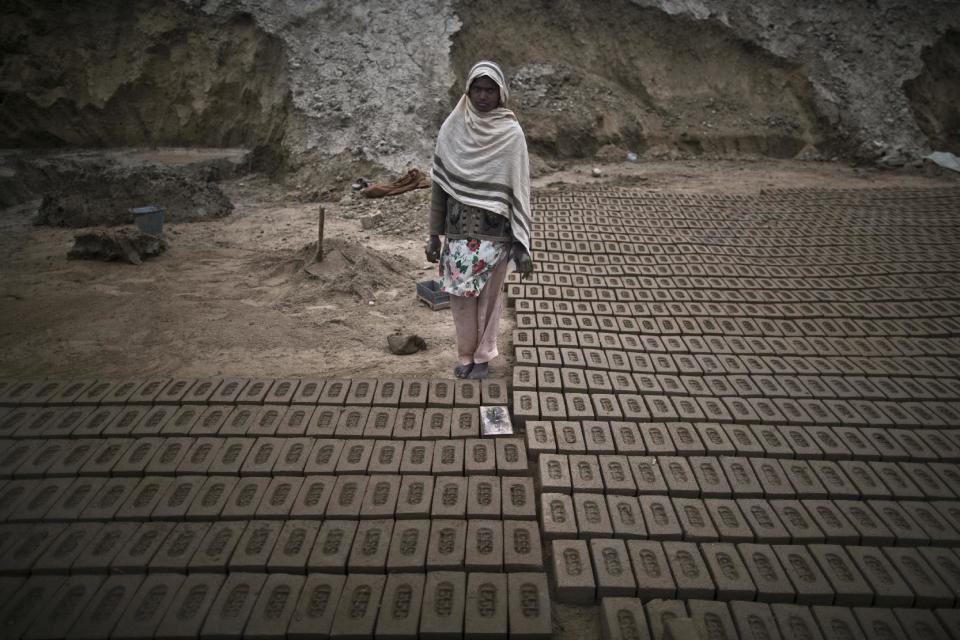 In this Monday, March 3, 2014, photo, Samina Manzoor, 27, a Pakistani brick factory worker, poses for a picture at the site of her work in Mandra, near Rawalpindi, Pakistan. Samina and her husband are in debt to their employer the amount of 300,000 rupees (approximately $3000). (AP Photo/Muhammed Muheisen)