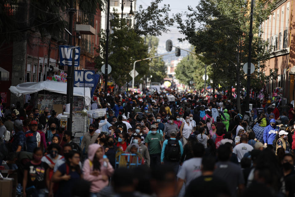 Shoppers, the vast majority wearing protective face masks, crowd a street in a commercial district of central Mexico City, Saturday, Dec. 5, 2020. With hospitals once again filling up with COVID-19 patients, Mexico City's mayor on Friday urged people to stay at home as much as possible and authorized checkpoints to limit the number of people entering the capital's colonial-era downtown at one time. (AP Photo/Rebecca Blackwell)