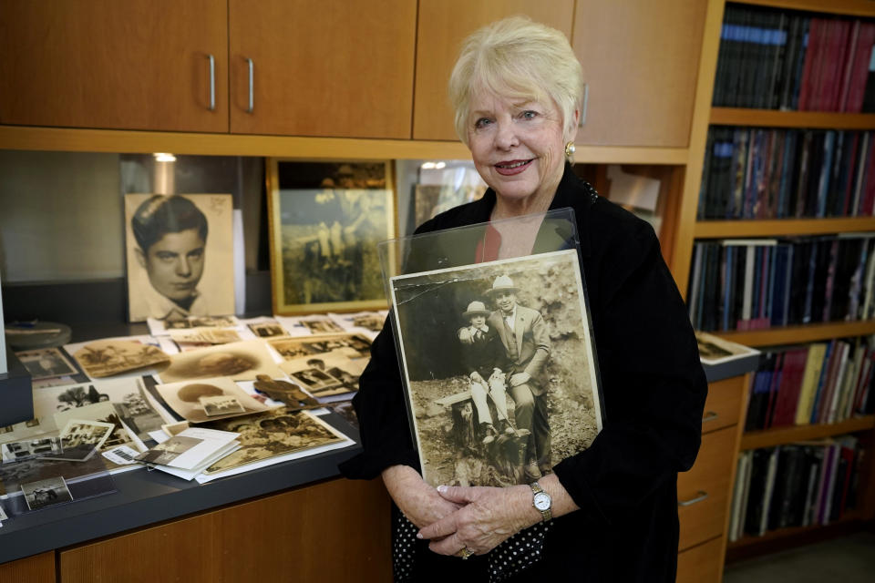 Diane Capone holds a copy of a photograph of her father, Albert "Sonny" Capone as a young boy and her grandfather Al Capone on display at Witherell's Auction House in Sacramento, Calif., Wednesday, Aug. 25, 2021. The granddaughter of the famous mob boss and her two surviving sisters will sell 174 family heirlooms at an Oct. 8 auction titled "A Century of Notoriety: The Estate of Al Capone," that will be held by Witherell's in Sacramento. (AP Photo/Rich Pedroncelli)