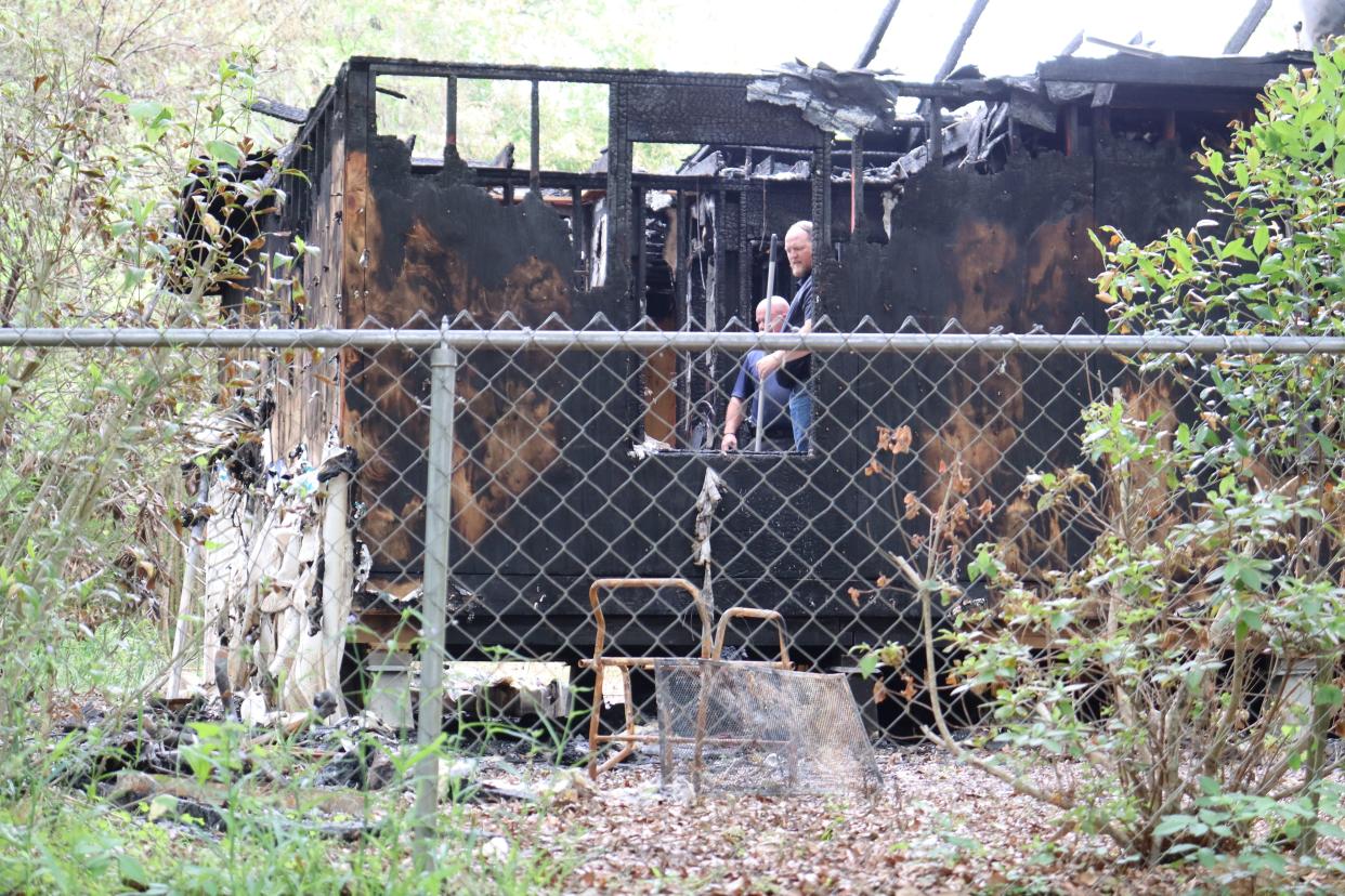 Investigators stand inside what's left of a Sanders Street home in Pineville on Friday, five days after a fire killed one person and wounded two others.