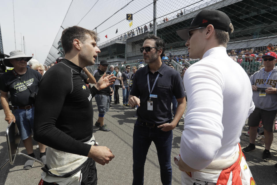 FILE - In this May 16, 2019, file photo, NASCAR driver Jimmie Johnson, center, talks with Will Power, left, of Australia, and Josef Newgarden during practice for the Indianapolis 500 IndyCar auto race at Indianapolis Motor Speedway in Indianapolis. NASCAR seven-time champion Jimmie Johnson will test an Indy car next week on the road course at Indianapolis Motor Speedway. He’s long said he is open to racing in the series but did not want to compete on ovals out of safety concerns. On Friday, July 3, 2020, he indicated recent safety improvements have softened his stance and the Indianapolis 500 is not entirely out of the picture(AP Photo/Darron Cummings)