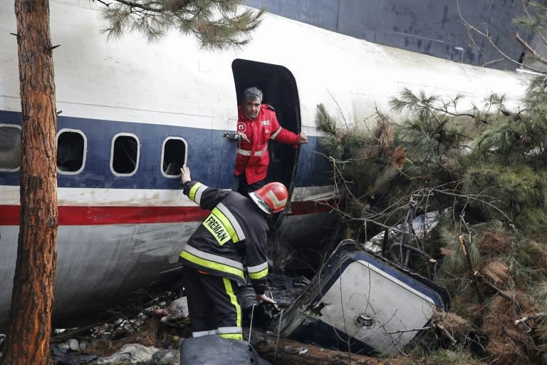 Firefighters examine the wreckage of a Boeing 707 cargo plane that slammed into a residential complex near the Iranian capital Tehran with at least 10 people onboard on January 14, 2019