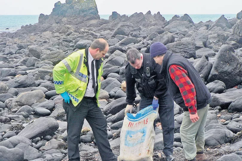 Police examine a large bag found on rocks in Cornwall