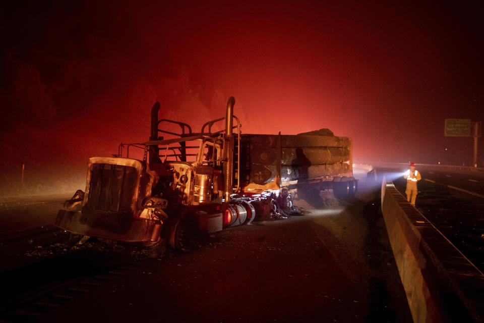 A scorched logging truck rests on Interstate 5 as the Delta Fire burns in the Shasta-Trinity National Forest, Calif., near Shasta Lake on Wednesday, Sept. 5, 2018. Parked trucks lined more than two miles of the highway as both directions remained closed to traffic. (AP Photo/Noah Berger)