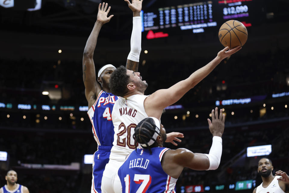 Cleveland Cavaliers forward Georges Niang (20) shoots against Philadelphia 76ers guard Buddy Hield (17) and forward Paul Reed during the second half of an NBA basketball game Friday, March 29, 2024, in Cleveland. (AP Photo/Ron Schwane)