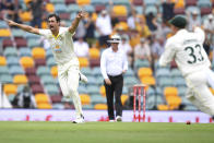 Australia's Mitchell Starc, left, celebrates after taking the wicket of England's Rory Burns during day one of the first Ashes cricket test between Australia and England at The Gabba in Brisbane, Australia, Wednesday, Dec. 8, 2021. (Darren England/AAP Image via AP)