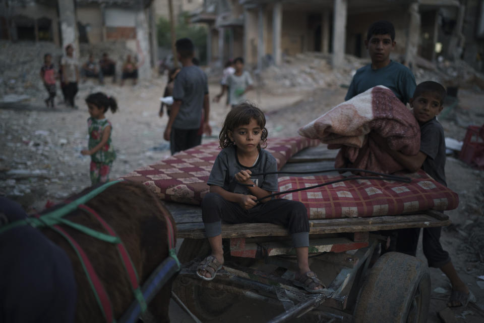 Chadi Nassir, 7, sits on a donkey cart as his brother, Mahmoud, loads it with belongings from their damaged house in Beit Hanoun, northern Gaza Strip, Sunday, June 13, 2021. (AP Photo/Felipe Dana)