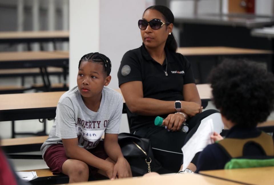 Renika Hendricks, of Reynoldsburg, and her son, Peyton Osborn, 11, listen as Patriot Prep athletics director Curt Caffey and football coaches discuss the beginning of the Eagles program this fall for middle school students.