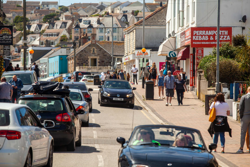 The Perranporth High Street in Cornwall, busy with visitors. 1st August 2020. See SWNS story SWPLtourism; Cornwall residents fear a local lockdown and say they are "scared to leave their houses"  - as some of the county's beaches are likened to "Benidorm on steroids". Some of the more popular seaside destinations along the south-west coast have seen trails of cars queuing through the town as visitors flock to beaches or holiday parks in search of a 'staycation'. But locals in these popular towns have been left feeling "uneasy" about leaving their homes - and some fear they could be in for a local lockdown set to be worse than the first lockdown. Tina-Marie Lally, from Penzance, tried to visit Porthminster Beach in St Ives last week - but shared photos on Facebook of the beach crowded with people and windbreakers.