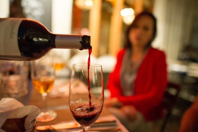 Red wine is poured into a glass at an outdoor Zurich restaurant.