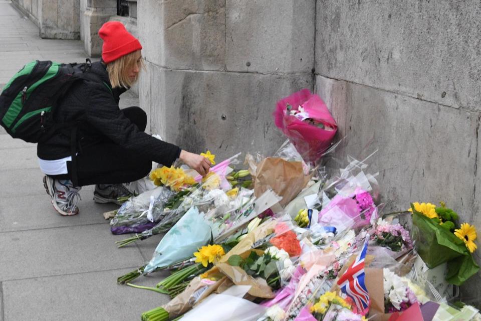 A woman lays flowers at the scene of the carnage in Westminster (Jeremy Selwyn)