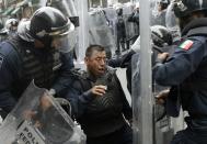 Riot policemen attend to a colleague who was injured during the protests in downtown Mexico City September 13, 2013. (REUTERS/Henry Romero)