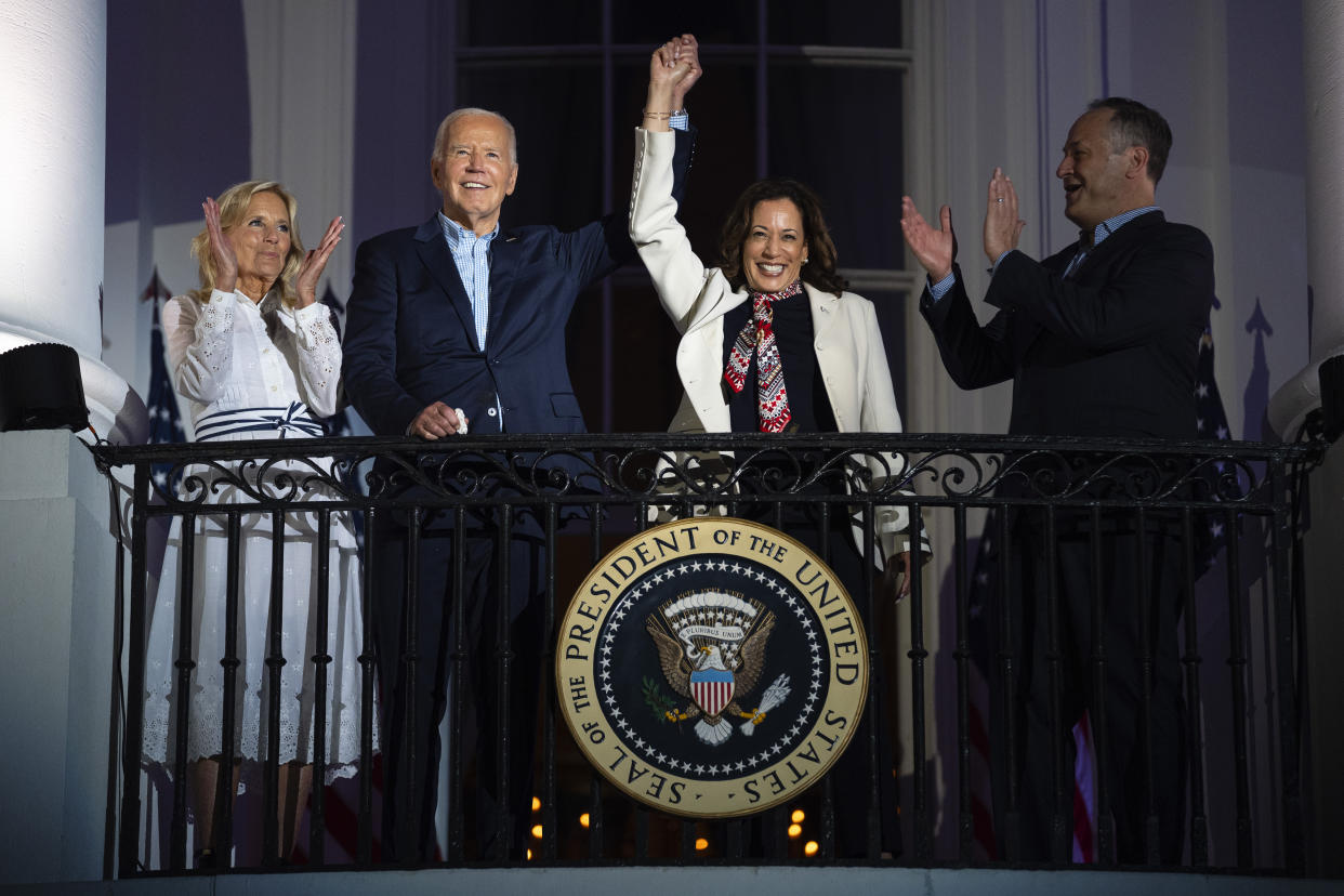 First lady Jill Biden and second gentleman Douglass Emhoff watch as President Joe Biden raises the hand of Vice President Kamala Harris on the balcony of the White House.