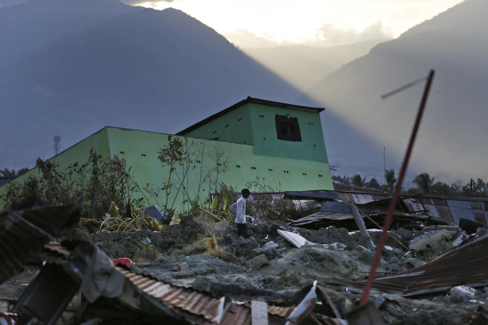 A man surveys the damage suffered byPetobo neighborhood which was wiped out by earthquake-triggered liquefaction as the sun set in Palu, Central Sulawesi, Indonesia, Sunday, Oct. 7, 2018. Indonesia's disaster agency said the number of dead had climbed and many more people could be buried, especially in the Palu neighborhoods of Petobo and Balaroa, where thousands of homes were damaged or sucked into deep mud when the Sept. 28 quake caused loose soil to liquefy. (AP Photo/Dita Alangkara)